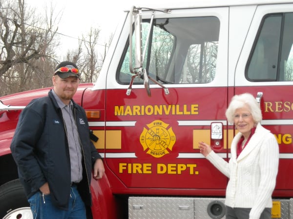 A resident poses next to a fire truck